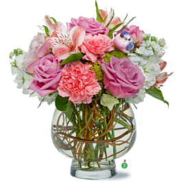 Round bouquet of pink roses and carnations with white blooms in a clear glass bowl vase