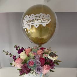 Bouquet of pastel roses in a white box with a gold congratulations balloon