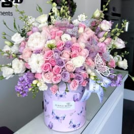 Large pastel bouquet of pink, lavender, and white roses in a butterfly-print box