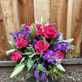 Bouquet of hot pink roses and purple flowers in a glass vase