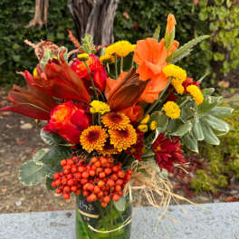 Orange and red bouquet in a glass vase with yellow blooms