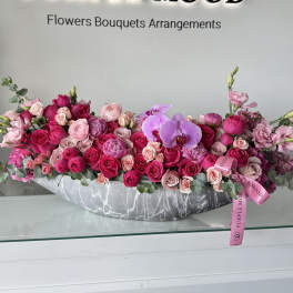 Long pink and purple flower arrangement in a gray vase
