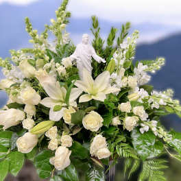 White lilies and roses arranged around a white religious figurine