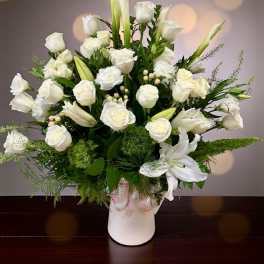 White roses and calla lilies arranged in a white vase