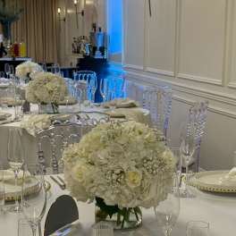White floral centerpieces on a formal banquet table with glassware