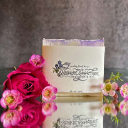 Pink roses and small pink blossoms arranged around a branded box