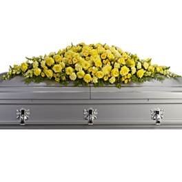 Long yellow rose casket spray arranged across a silver casket