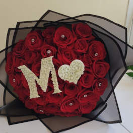 Heart-shaped bouquet of red roses with a white "M" and heart topper