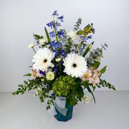 Blue and white floral arrangement in a blue vase with a ribbon