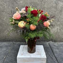 Mixed bouquet of red and peach roses in a brown glass vase