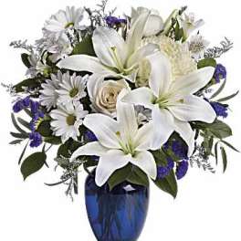 White lilies and daisies in a blue glass vase