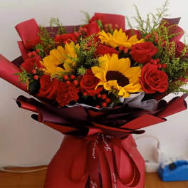 Bouquet of red roses and yellow sunflowers wrapped in red paper