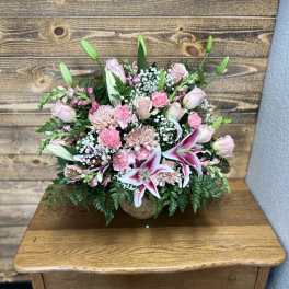 Pink floral arrangement with lilies and roses in a low vase