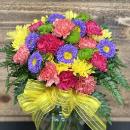 Colorful mixed bouquet in a glass vase with a yellow ribbon
