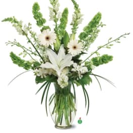 Tall white lily and gerbera arrangement with green Bells of Ireland in a clear glass vase