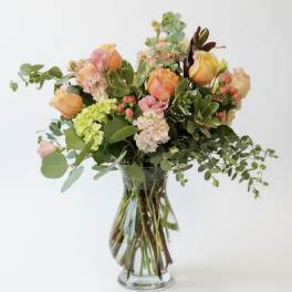 Mixed bouquet of peach and pink roses in a clear glass vase