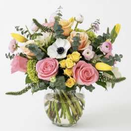 Mixed bouquet of pink and yellow flowers in a clear glass vase