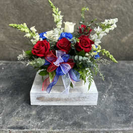 Red roses and white snapdragons arranged in a wooden box with ribbon