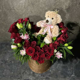 Red rose arrangement with lilies and a teddy bear in a woven basket