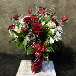 Red roses and white flowers in a vase with heart picks and ribbon
