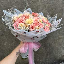 Bouquet of pink and yellow roses wrapped in Hello Kitty paper with a pink ribbon