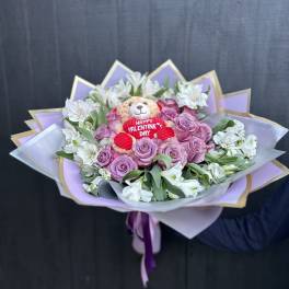 Bouquet of pink roses and white flowers with a teddy bear in the center