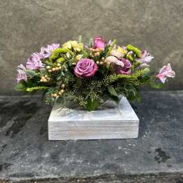 Low floral arrangement with pink and yellow roses in a wooden box