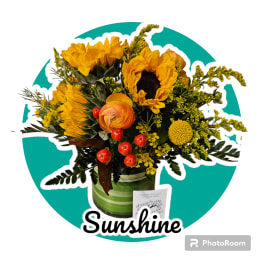 Sunflower bouquet with orange ranunculus in a green striped container