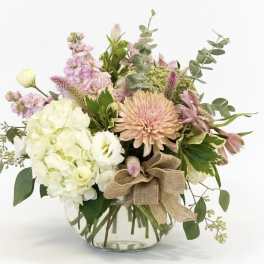 Mixed pastel bouquet in a clear glass vase with a burlap bow