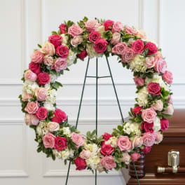 Heart-shaped wreath of pink and white roses on a stand