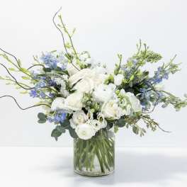 White and blue floral arrangement in a clear glass vase