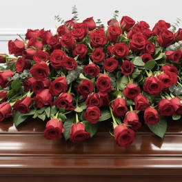 Large red rose casket spray on a wooden casket