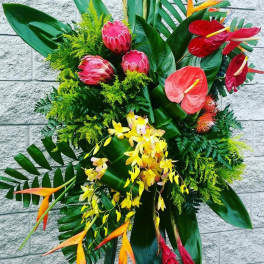 Tropical floral arrangement with red anthuriums, pink protea, and yellow orchids