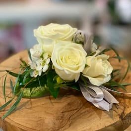 White rose corsage with small white blossoms and a silver ribbon