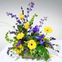 Yellow and purple mixed flower arrangement in a rectangular container