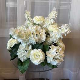 White floral arrangement with hydrangeas and roses in a clear vase