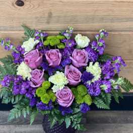 Bouquet of pink roses, purple flowers, and green mums in a dark vase