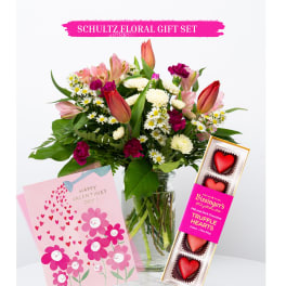 Mixed bouquet in a glass vase with a Valentine card and heart-shaped chocolates