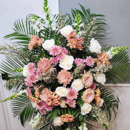 Large standing floral spray with pink and white blooms and palm fronds