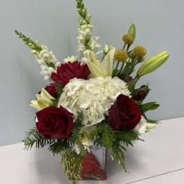Red roses and white hydrangea in a square vase with lilies and snapdragons