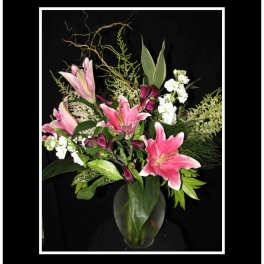 Pink lilies and white flowers arranged in a glass vase
