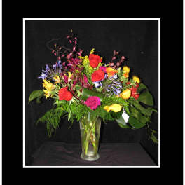 Mixed bouquet of red roses and colorful flowers in a clear glass vase