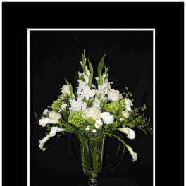 White flowers and green blooms arranged in a clear glass vase