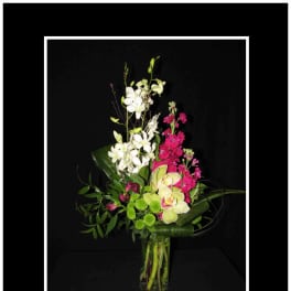 Tall orchid arrangement in a clear glass vase with white and pink blooms