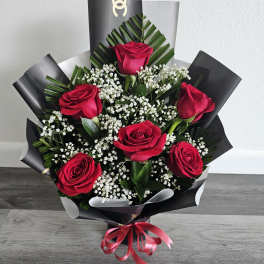 Bouquet of red roses with baby's breath in black wrap and pink ribbon