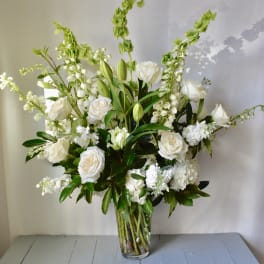 White floral arrangement in a clear glass vase with tall green spikes