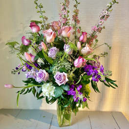 Tall bouquet of pink and lavender roses in a clear glass vase