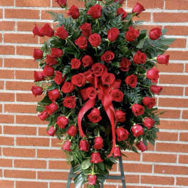 Standing spray of red roses with a red ribbon on a black easel