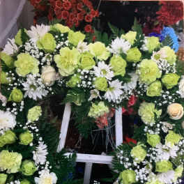 Large floral wreath on a white stand with lime green and white flowers