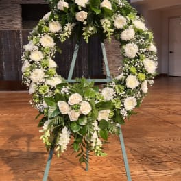 Large white floral wreath on a stand with roses and chrysanthemums